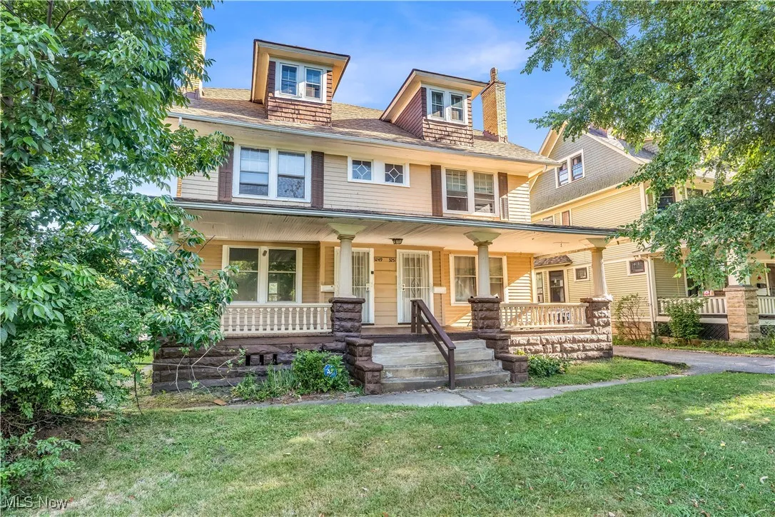 American foursquare style home featuring a porch, a front yard, and a chimney