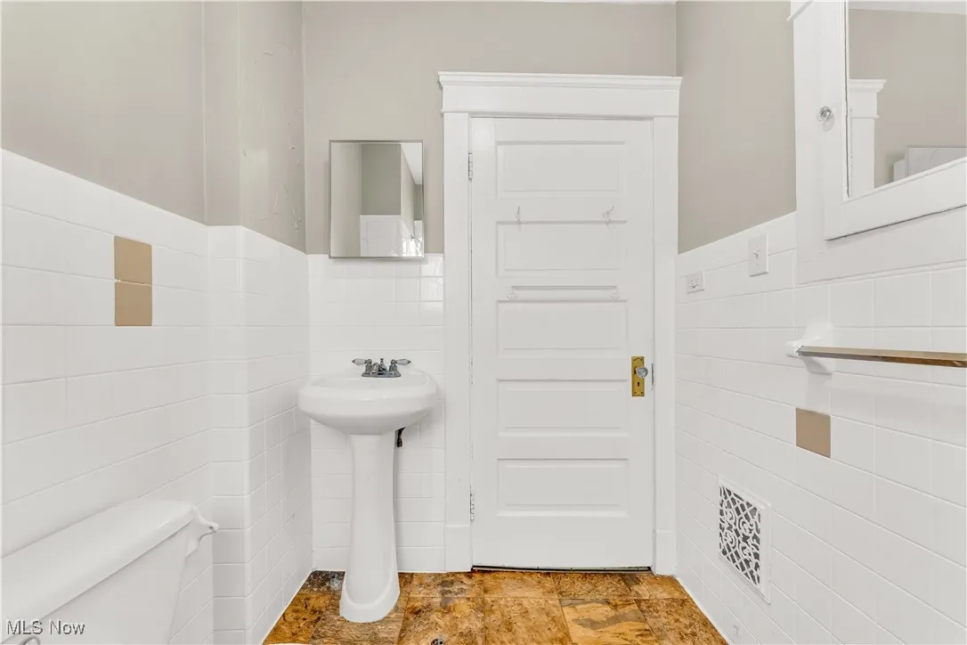 Half bath with tile walls and wainscoting