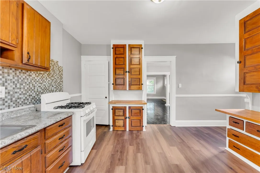 Kitchen featuring white range with gas cooktop, brown cabinets, and light countertops