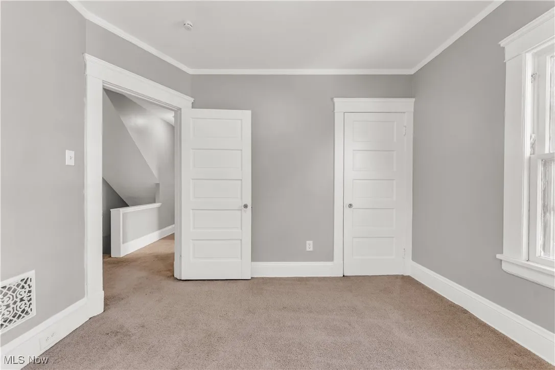 Unfurnished bedroom with light carpet and crown molding