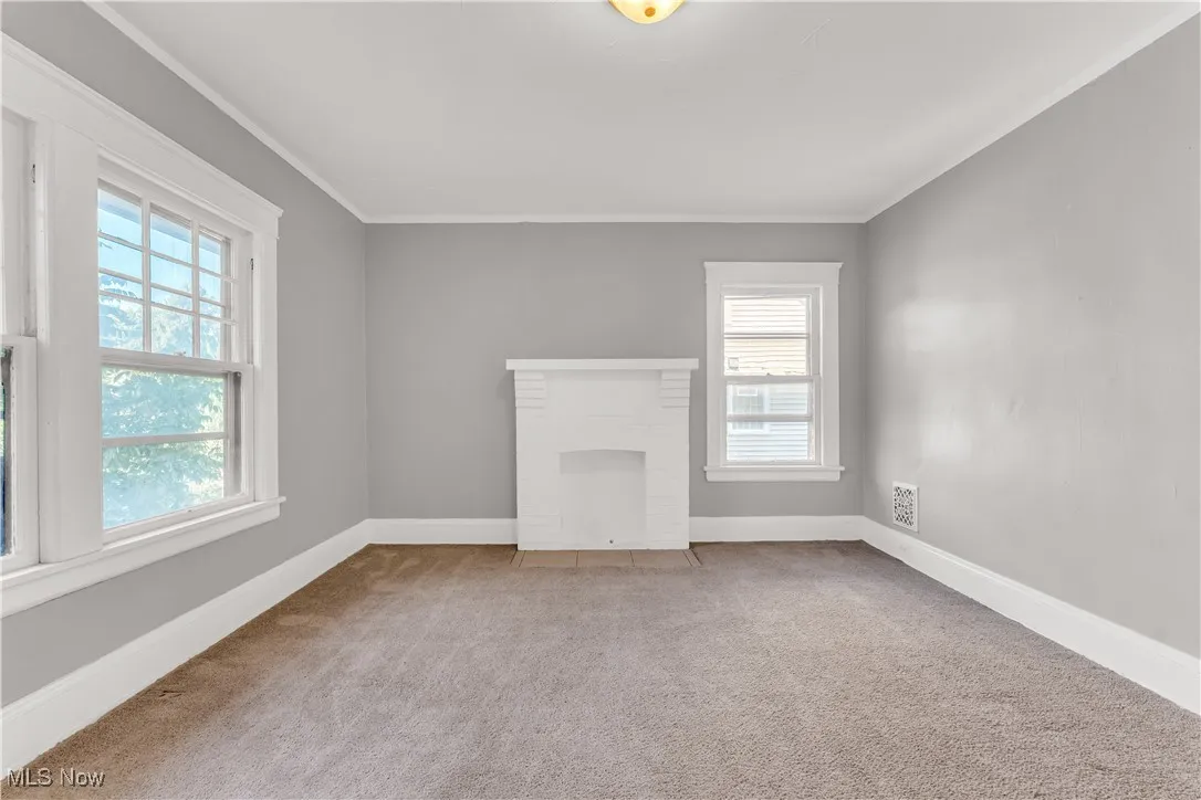 Unfurnished living room featuring carpet flooring and crown molding