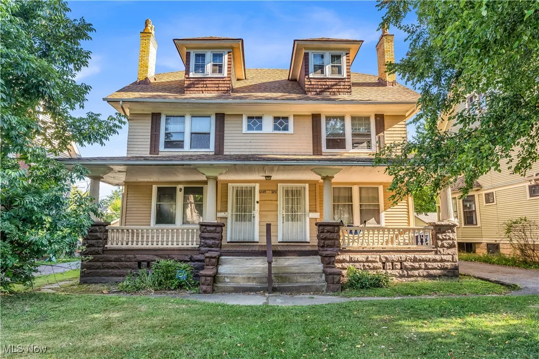 Traditional style home featuring a chimney, a porch, a front lawn, and roof with shingles