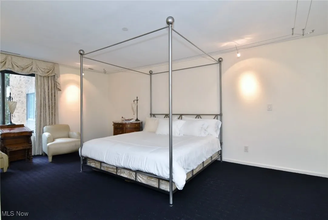 Bedroom featuring dark carpet and baseboards