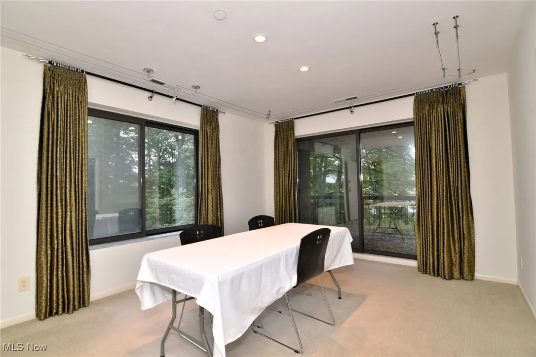 Dining room with light colored carpet and recessed lighting