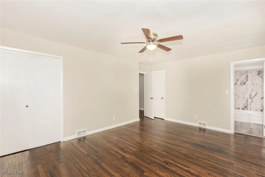 Unfurnished bedroom with dark wood-type flooring and ceiling fan