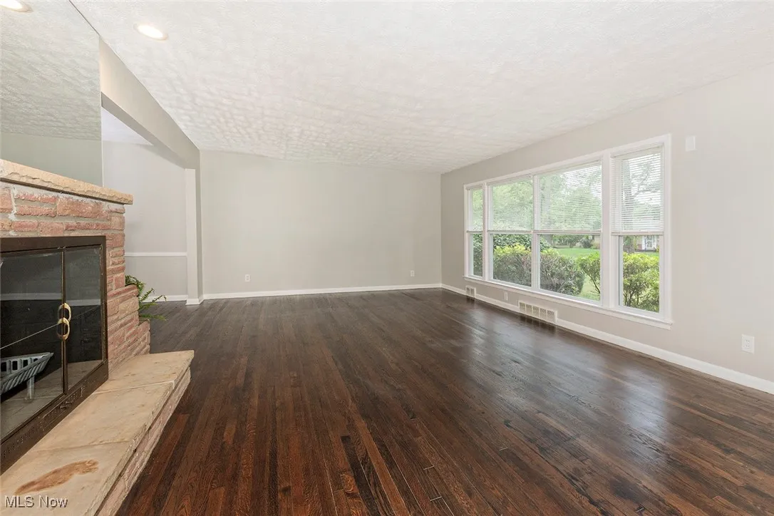 Unfurnished living room with dark wood-style flooring, a glass covered fireplace, a textured ceiling, and recessed lighting