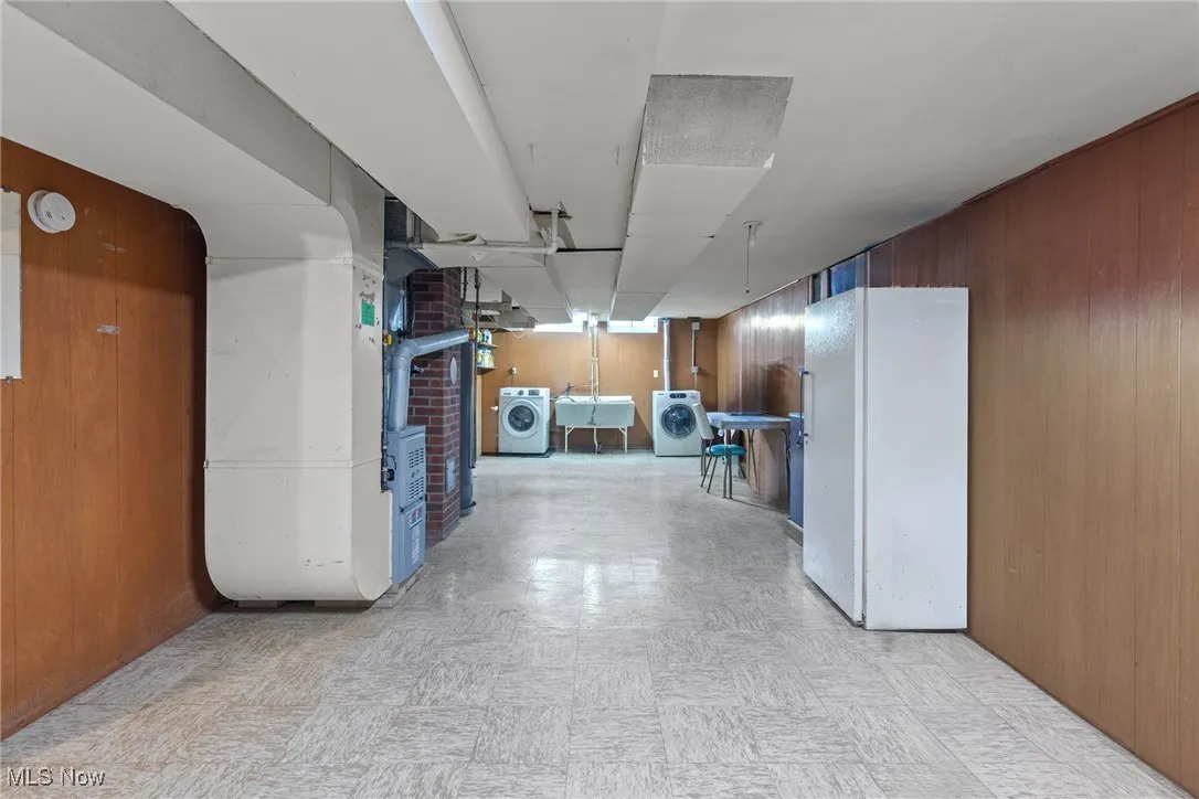Corridor with wooden walls, light floors, and separate washer and dryer