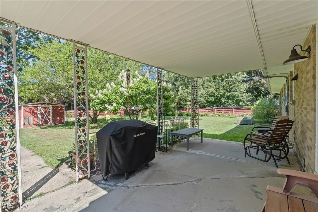 View of patio / terrace with area for grilling, a storage shed, and view of scattered trees