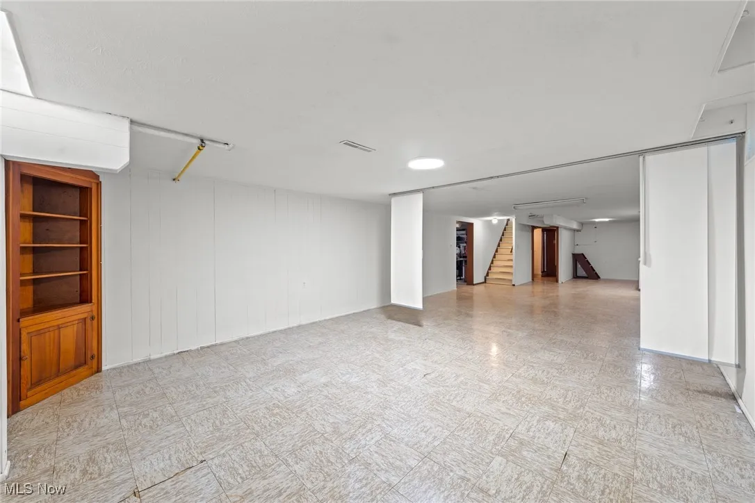 Finished basement featuring light floors and stairway