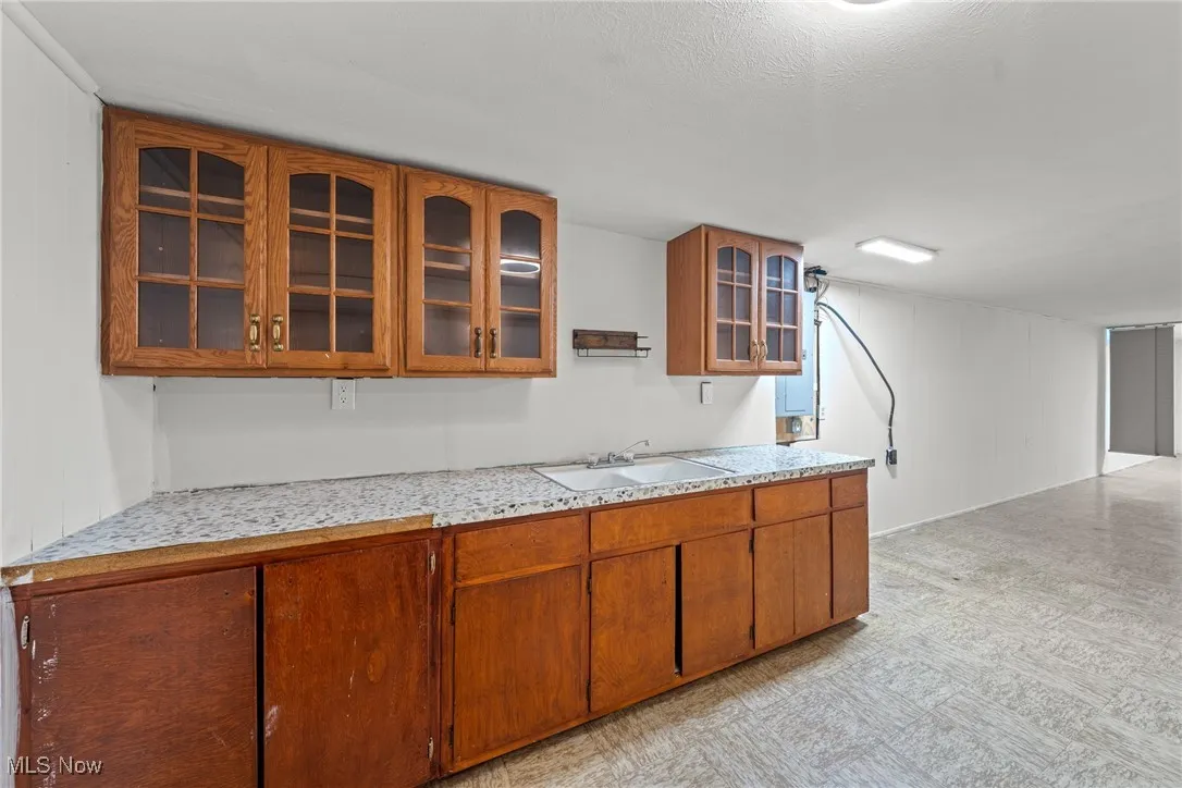 Kitchen with glass insert cabinets, brown cabinets, and wooden walls