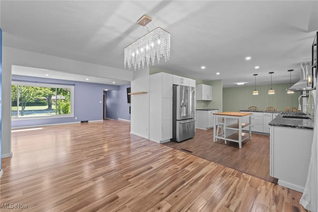 Kitchen with white cabinets, decorative light fixtures, high end refrigerator, dark wood-style floors, and recessed lighting