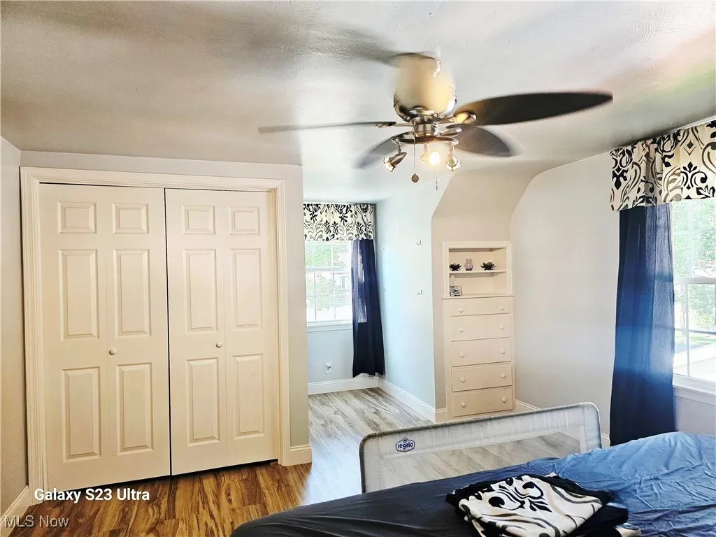 Bedroom with wood finished floors, a ceiling fan, and a closet
