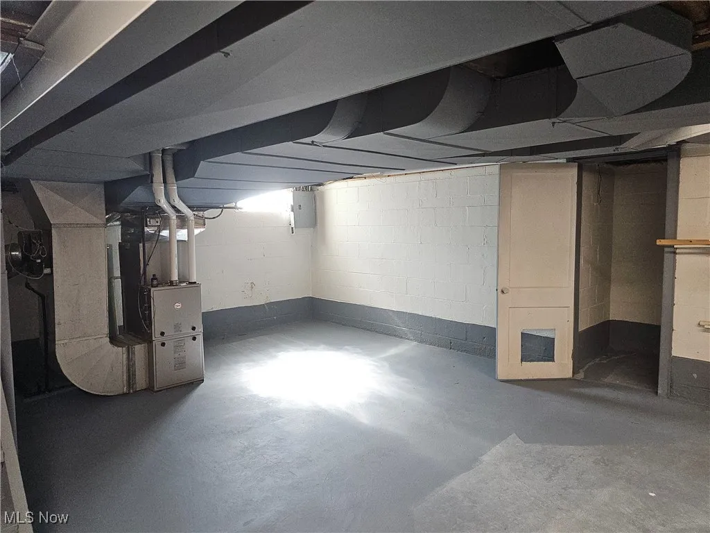 Unfinished basement featuring electric panel and heating unit