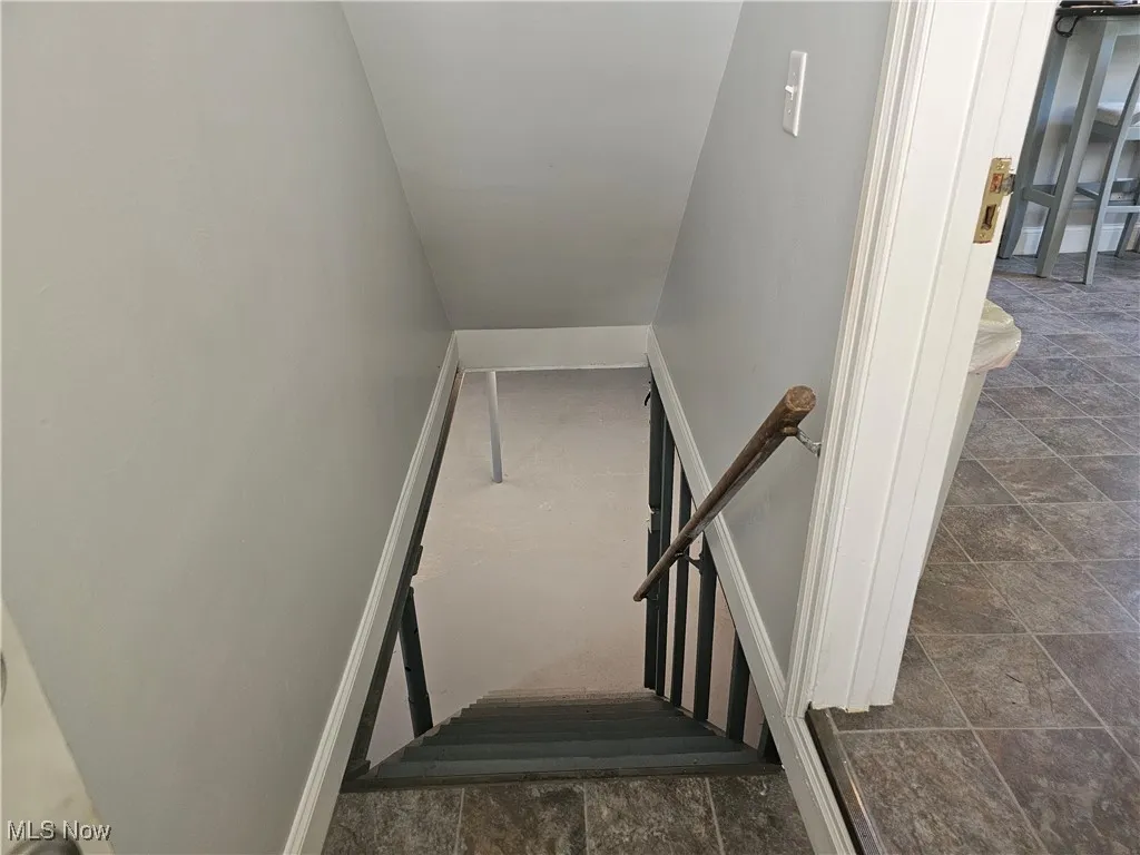 Stairs featuring stone finish floors and baseboards