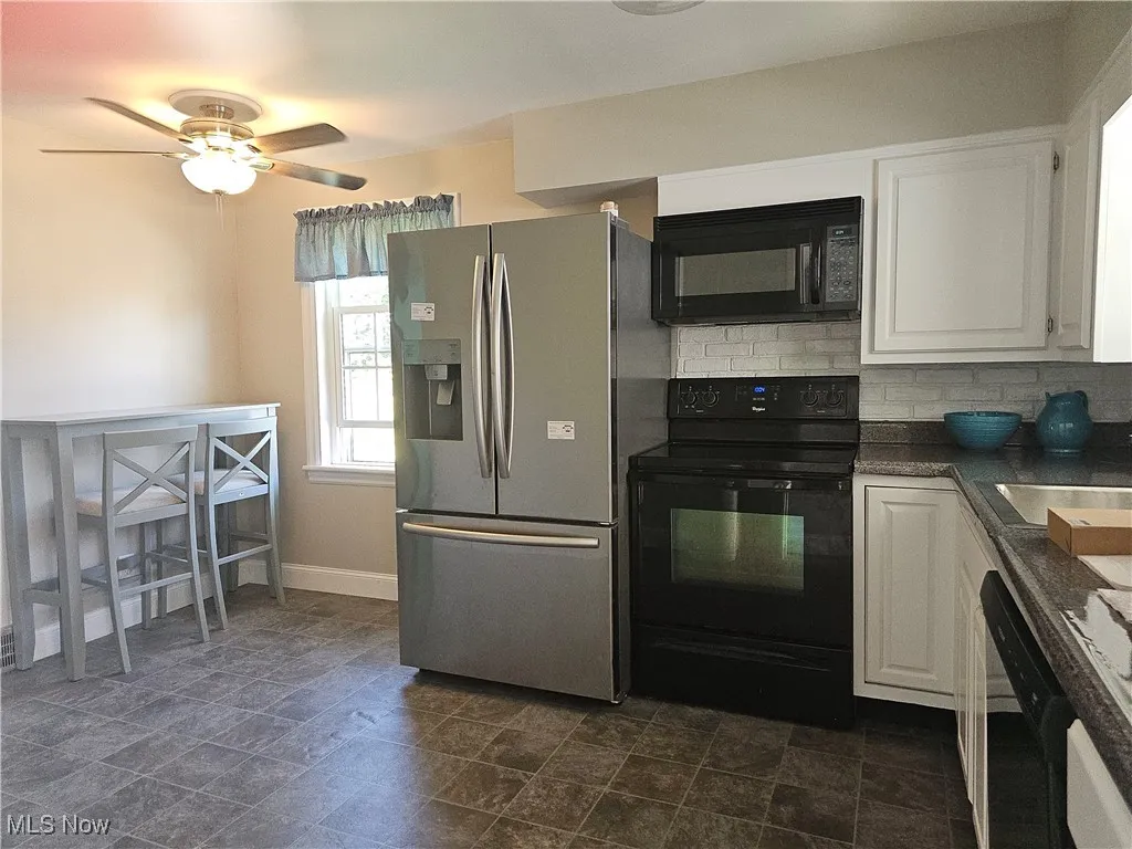 Kitchen with black appliances, white cabinets, tasteful backsplash, and ceiling fan