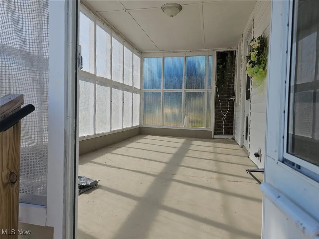 Unfurnished sunroom with concrete flooring