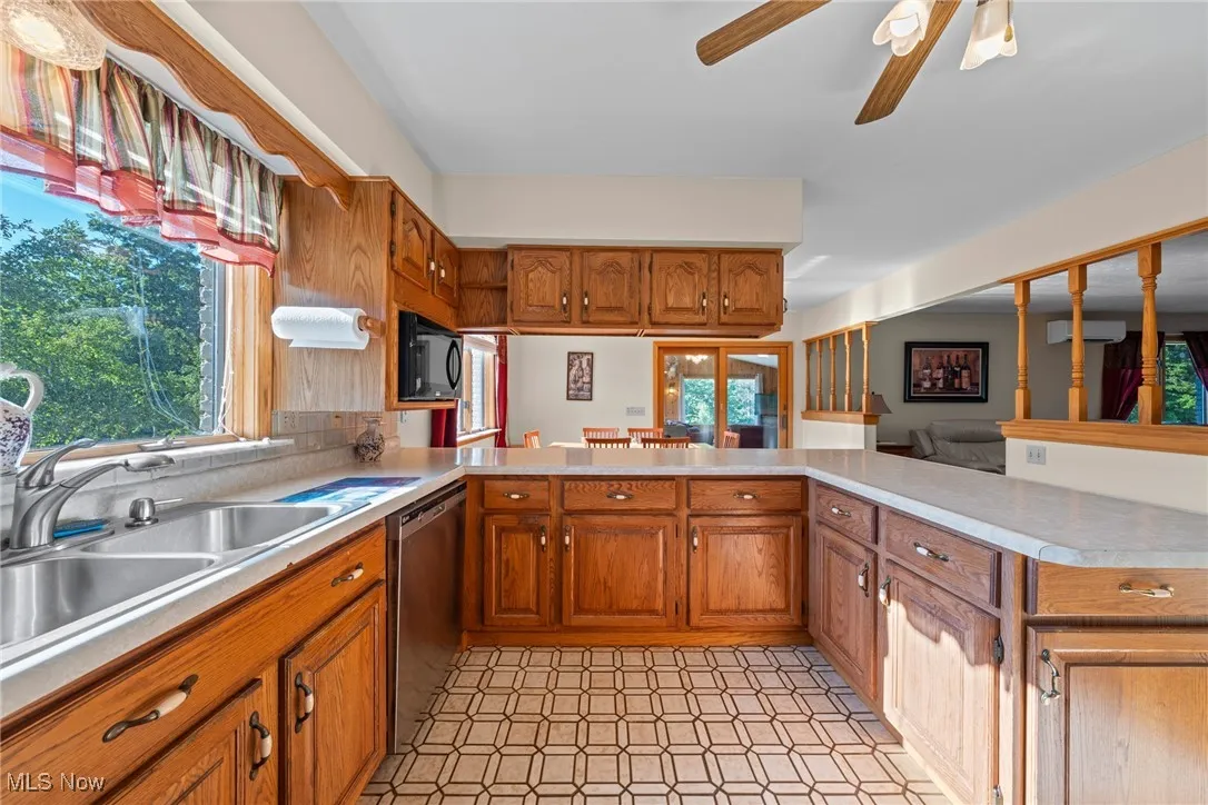 Kitchen with light countertops, light flooring, ceiling fan, brown cabinetry, and dishwasher
