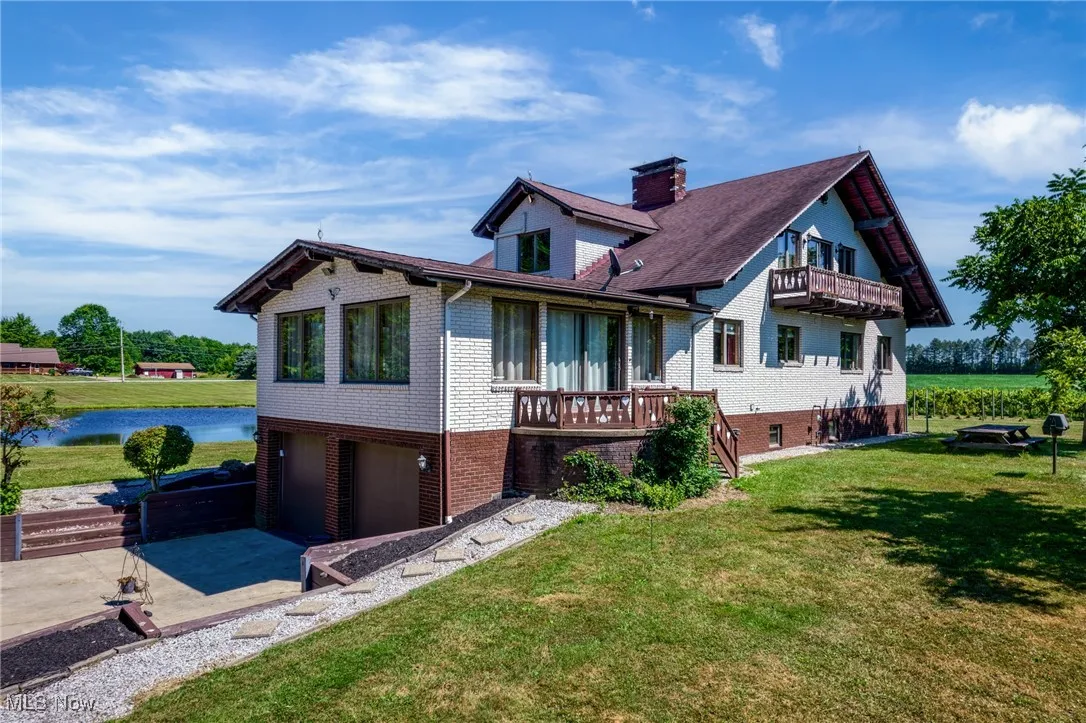 Rear view of house with brick siding, a garage, a lawn, and a balcony