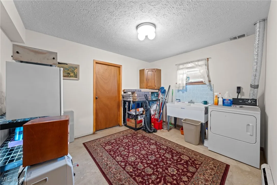 Washroom featuring washer / clothes dryer, a textured ceiling, and a baseboard heating unit