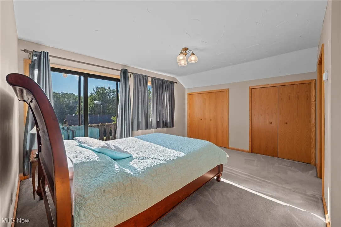 Bedroom with carpet flooring, multiple closets, and lofted ceiling
