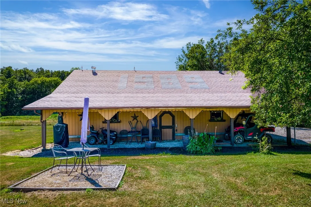Rear view of property featuring a yard, a shingled roof, and a patio