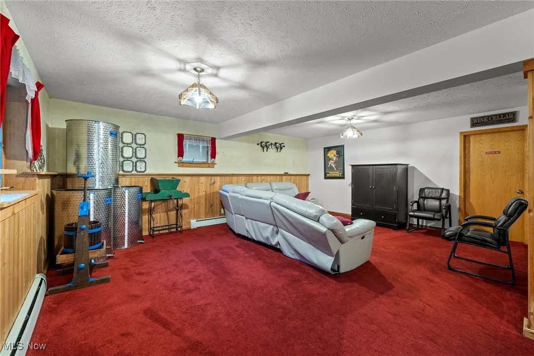 Carpeted bedroom featuring a baseboard heating unit, wood walls, and a textured ceiling