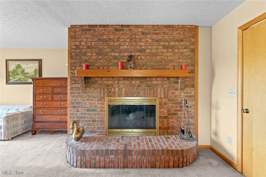 Detailed view of carpet floors, a fireplace, and a textured ceiling