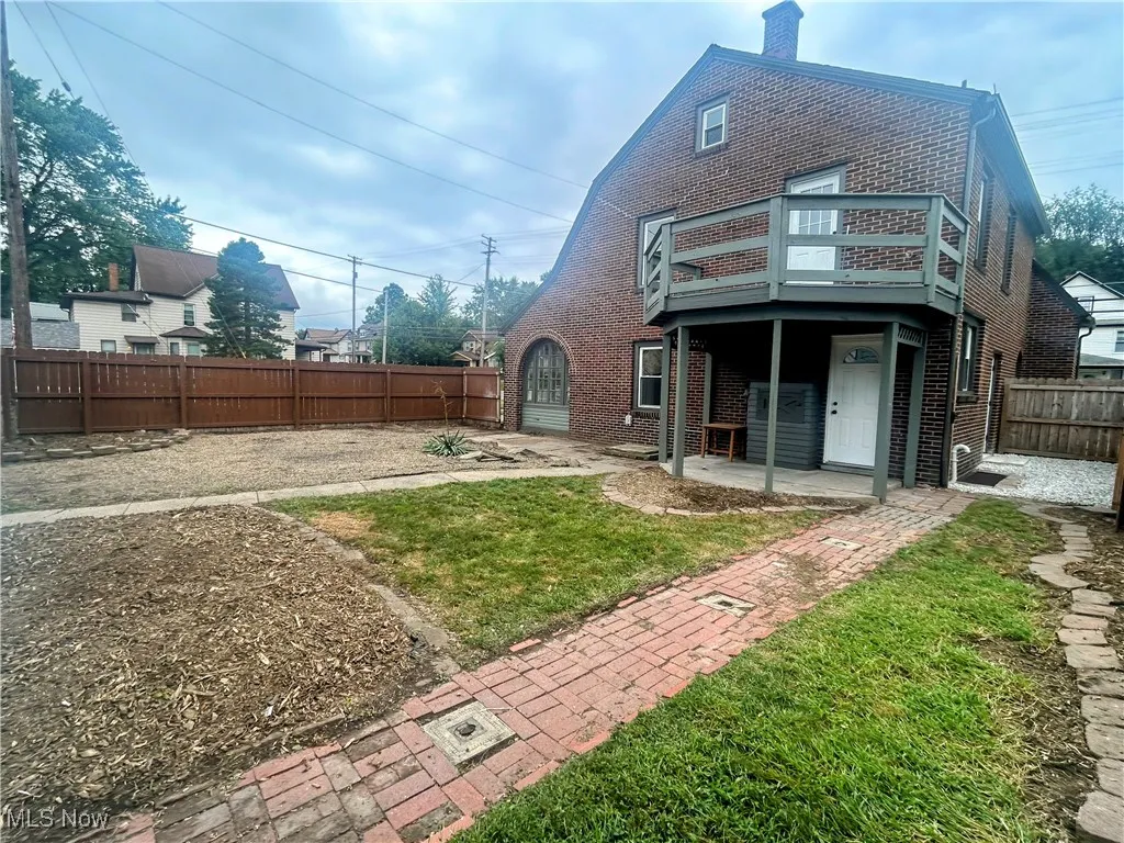 Rear view of property featuring a fenced backyard, brick siding, and a chimney