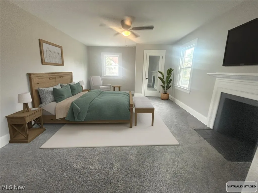 Bedroom with carpet floors, ceiling fan, access to exterior, and a fireplace with flush hearth