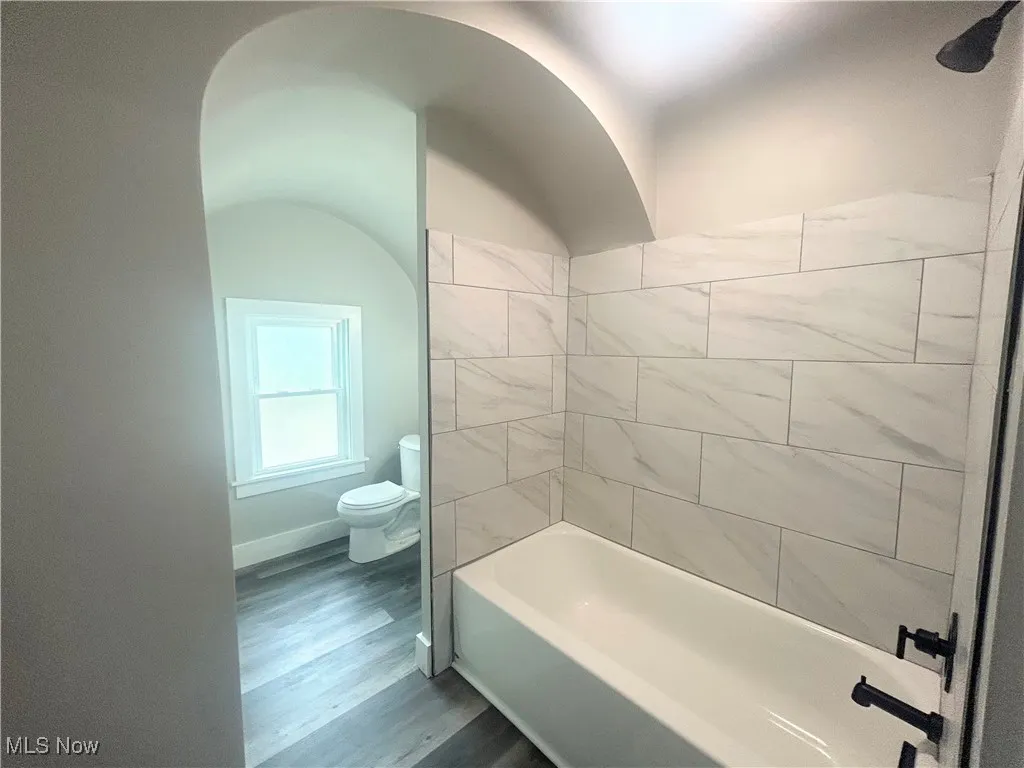 Full bath featuring dark wood-style floors and washtub / shower combination
