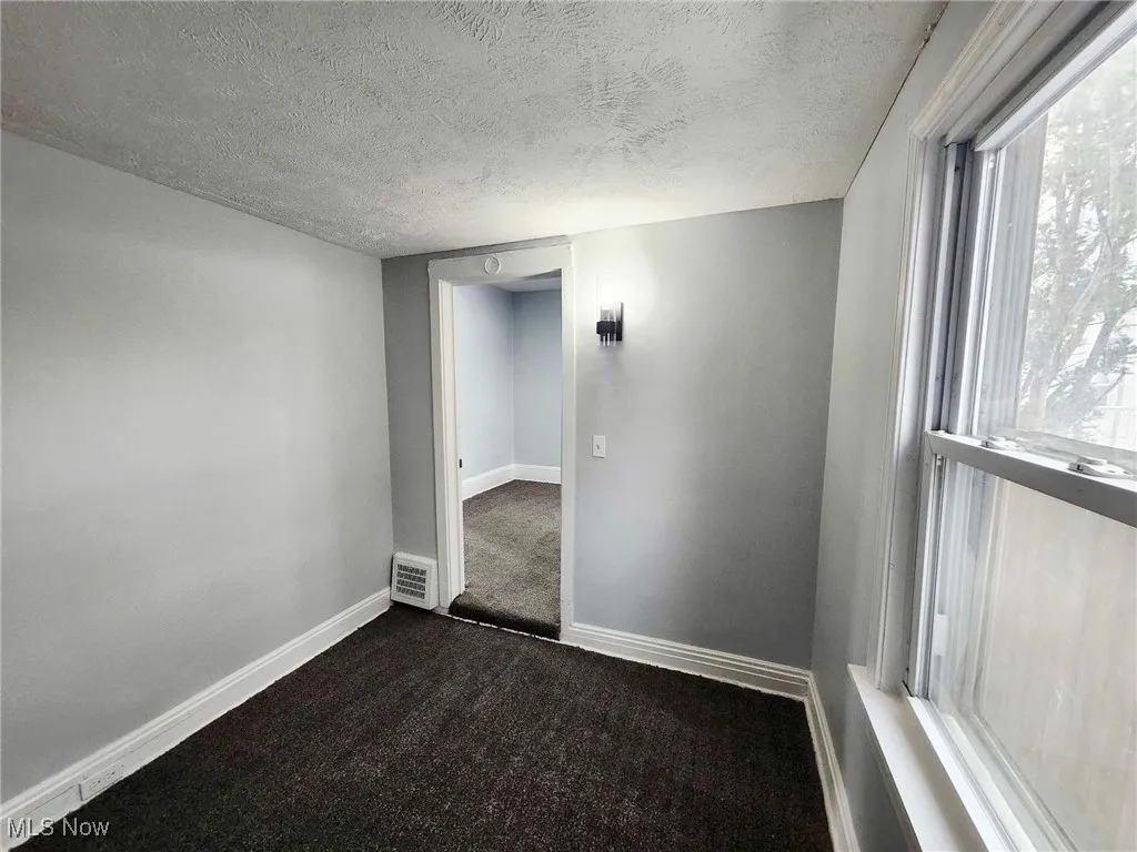 Spare room featuring a textured ceiling and dark colored carpet