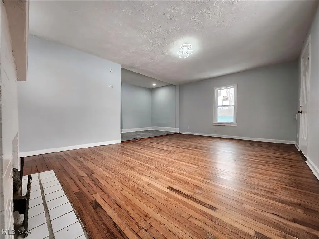 Empty room with light wood-style flooring and a textured ceiling