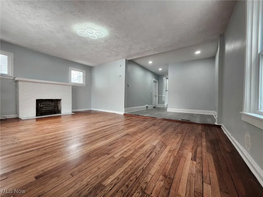 Unfurnished living room featuring hardwood / wood-style floors, a fireplace, and a textured ceiling