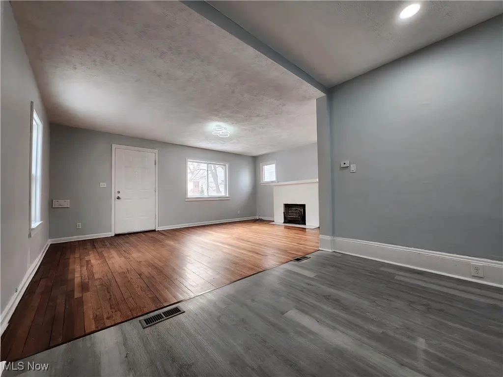 Unfurnished living room featuring dark wood finished floors, a fireplace, and a textured ceiling