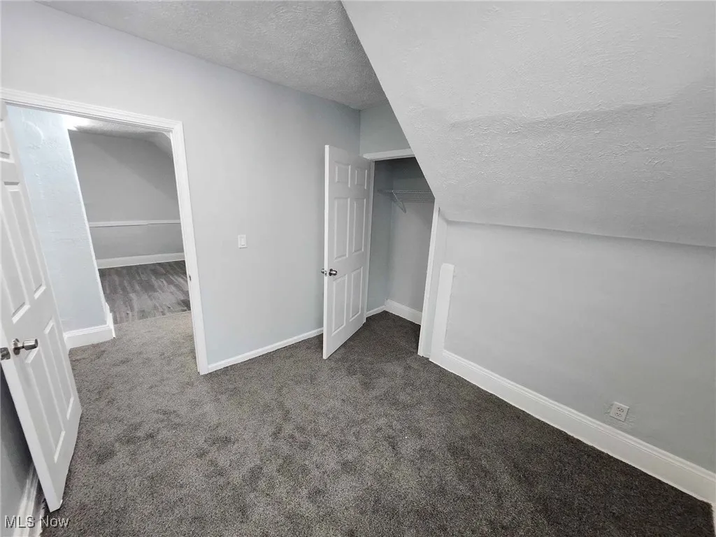 Additional living space featuring a textured ceiling and carpet floors
