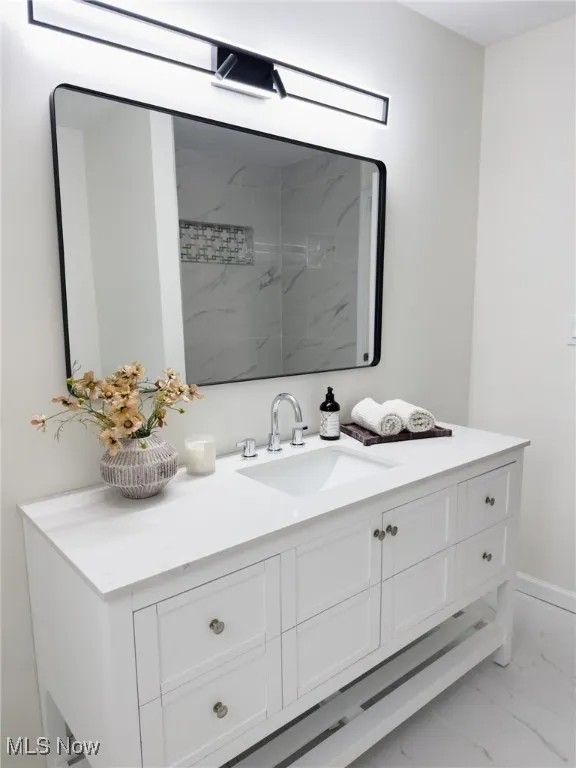 Bathroom with vanity, light marble finish flooring, and a marble finish shower