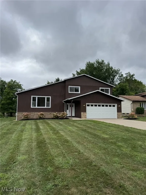 View of front facade with concrete driveway, a front lawn, and a garage