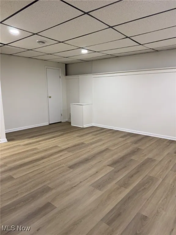 Finished below grade area featuring a drop ceiling and light wood-style floors