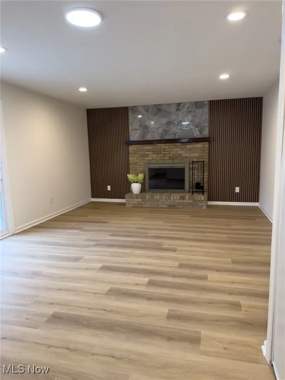 Unfurnished living room with a brick fireplace, light wood finished floors, and recessed lighting