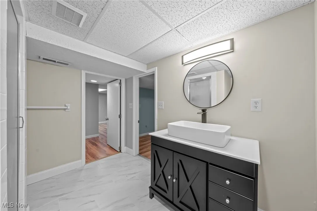 Bathroom with vanity, light marble finish flooring, and a paneled ceiling