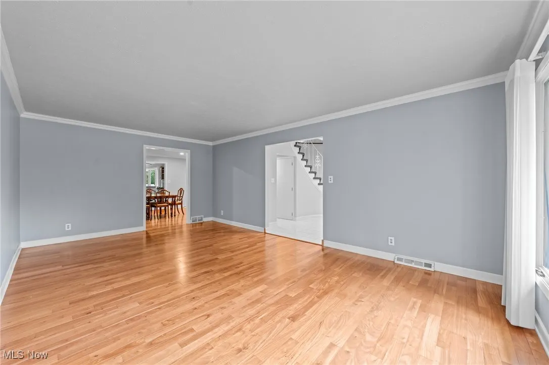 Unfurnished room with ornamental molding, light wood finished floors, and stairs