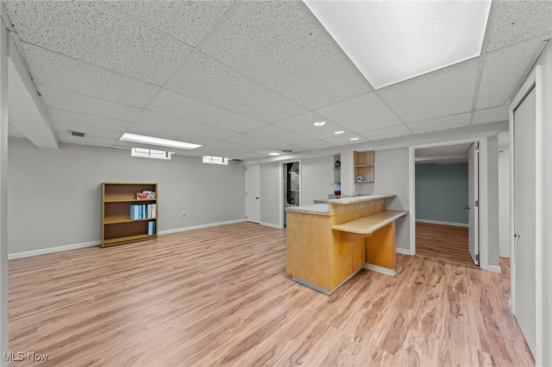 Kitchen featuring light wood-type flooring, a peninsula, light countertops, open floor plan, and a kitchen bar