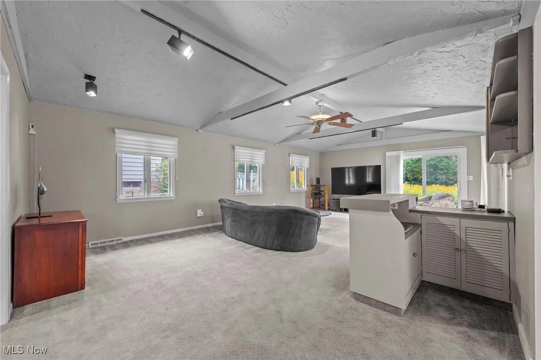 Living area featuring a textured ceiling, rail lighting, light carpet, and ceiling fan