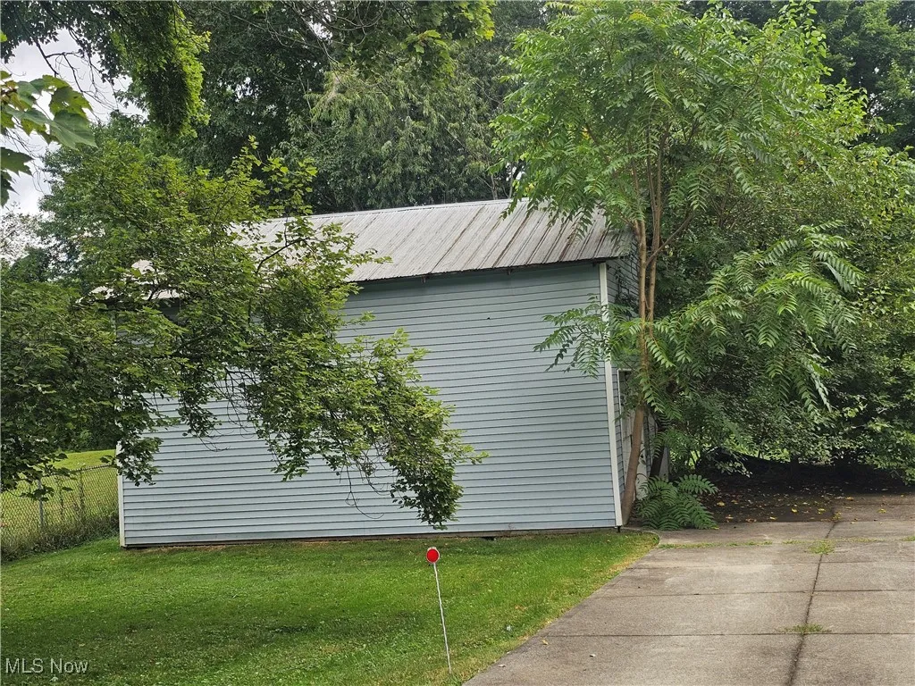 View of property exterior with a yard, an outdoor structure, and a metal roof