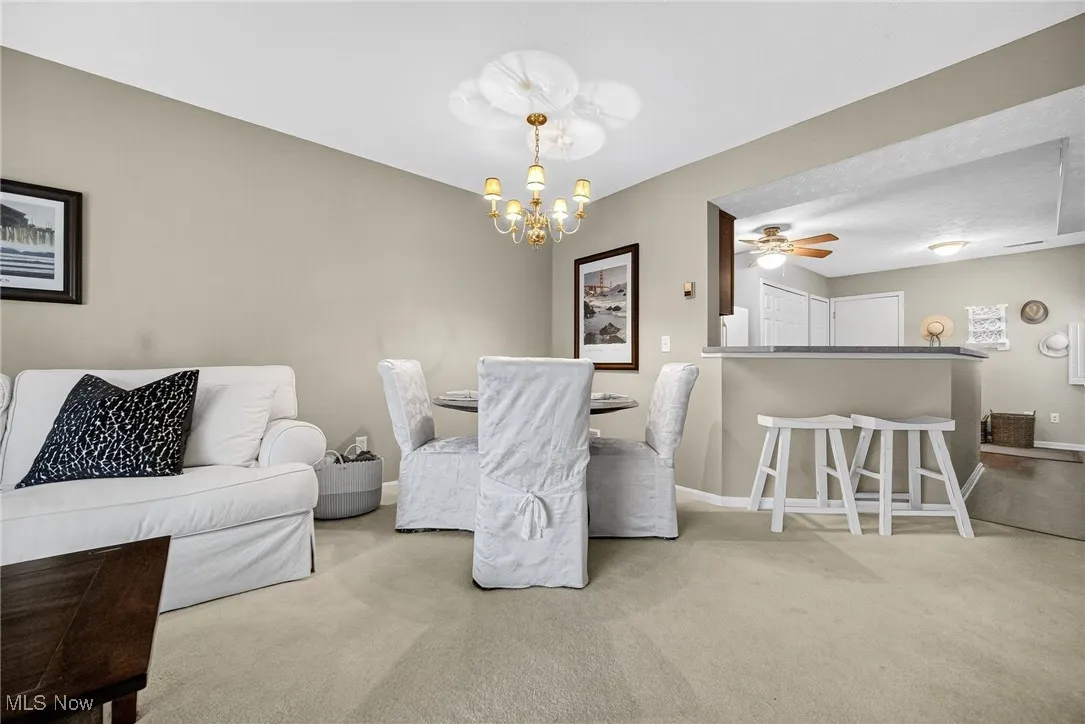 Dining space with a ceiling fan, light colored carpet, and a chandelier