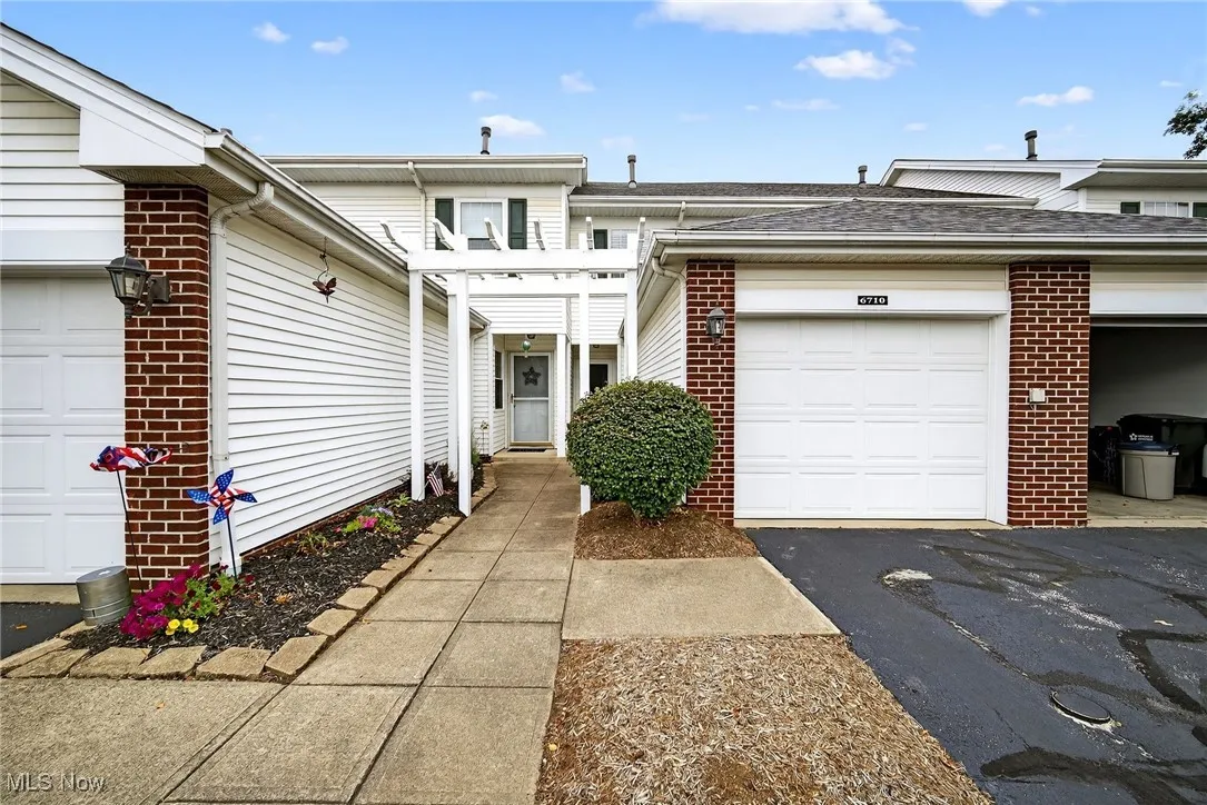 Traditional-style house featuring brick siding, a shingled roof, and a garage