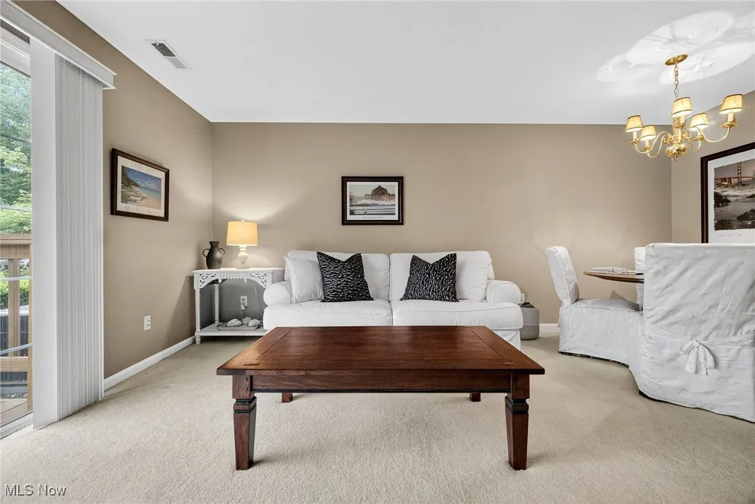Carpeted living area featuring plenty of natural light and a chandelier
