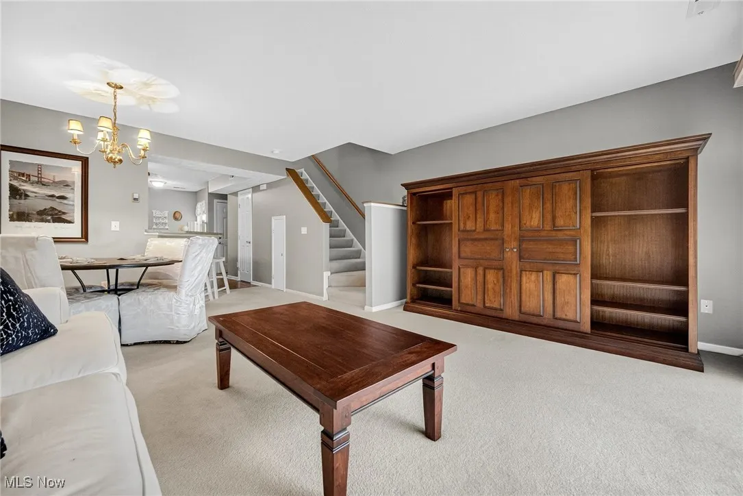 Living area featuring stairway, light colored carpet, and a chandelier