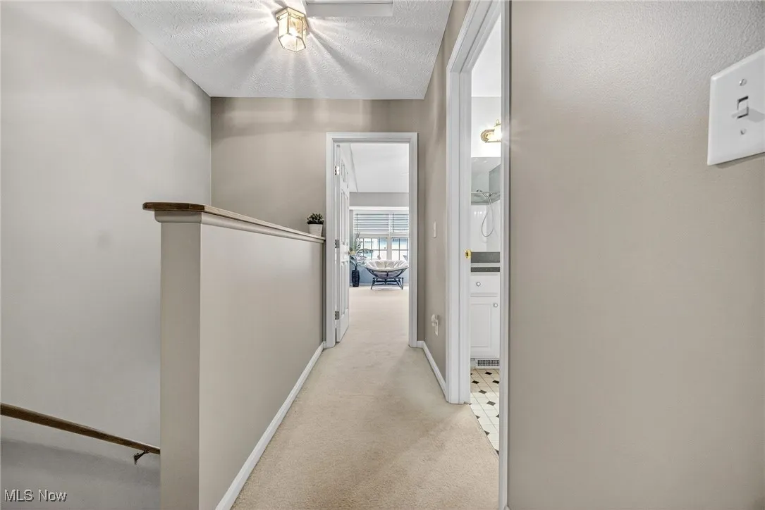 Hallway with light colored carpet and a textured ceiling