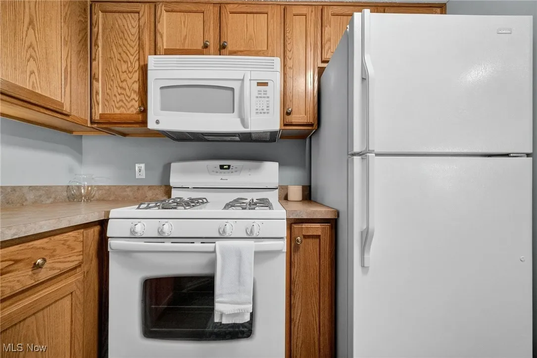 Kitchen with white appliances, brown cabinets, and light countertops